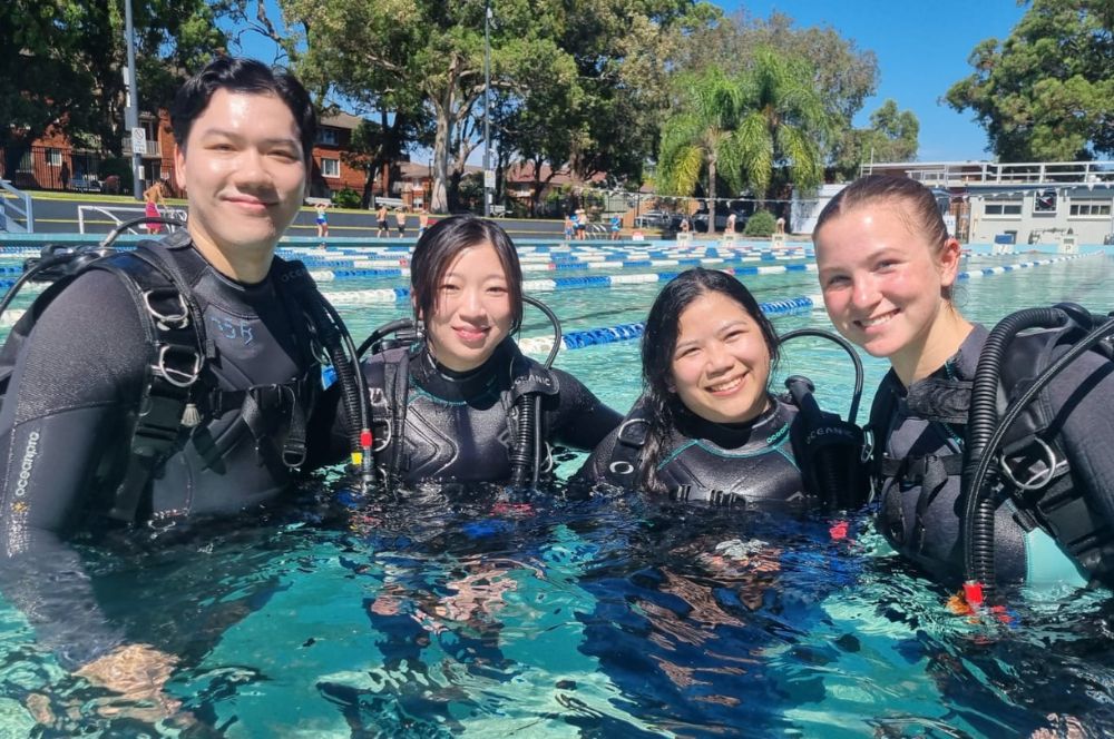 A group of divers preparing for their first dive lesson in a pool.